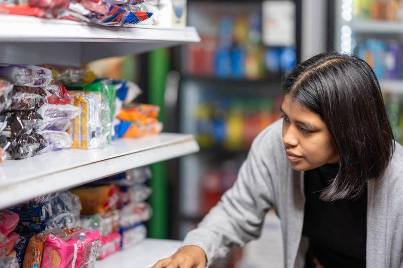Latina young woman buying products in a small supermarket