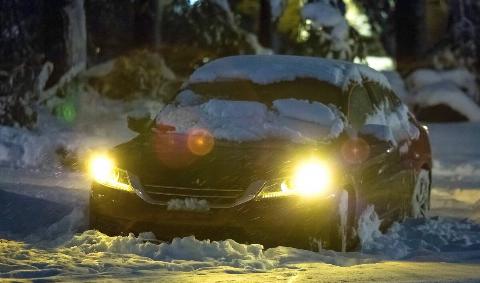 A car with its lights on in the snow.