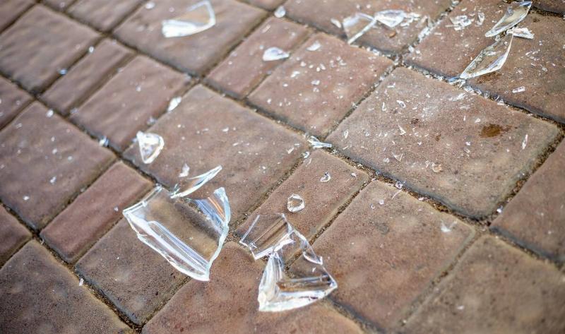 Some pieces of shattered glass on a brick floor.