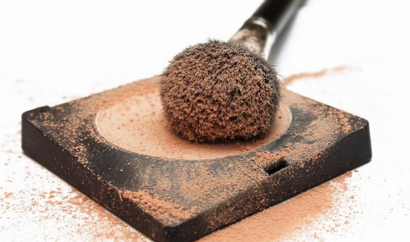 A closeup of some powder foundation with a large brush in it.