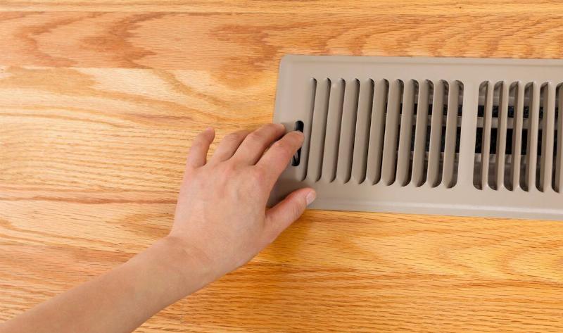 A hand closing a floor vent with the switch.