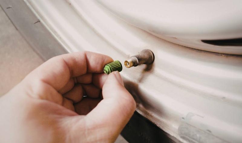 Someone screwing a green valve cap on.