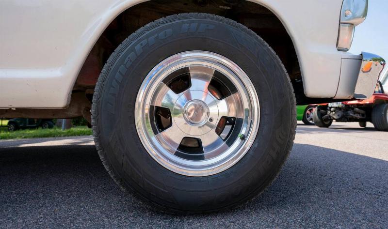 A car tire with a green valve cap.