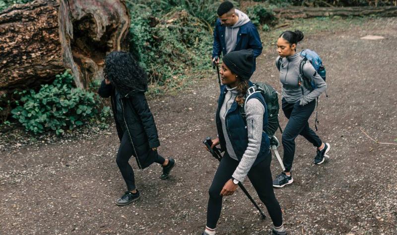 A group of friends, all in dark pants, hiking together.