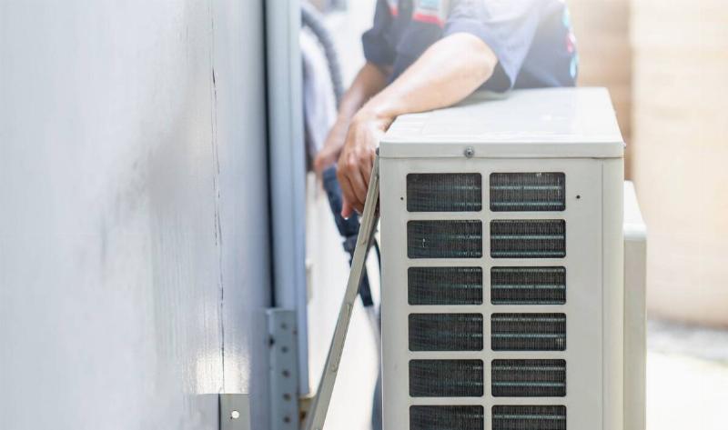 A repairman trying to access a furnace.