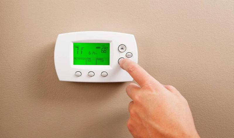 A person adjusting a thermostat.