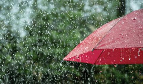 A red umbrella under falling rain.