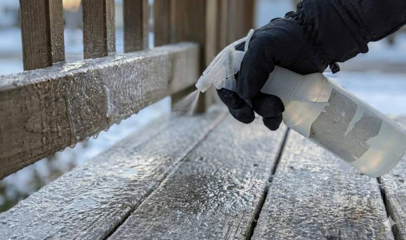 A person using a spray bottle an icy porch.