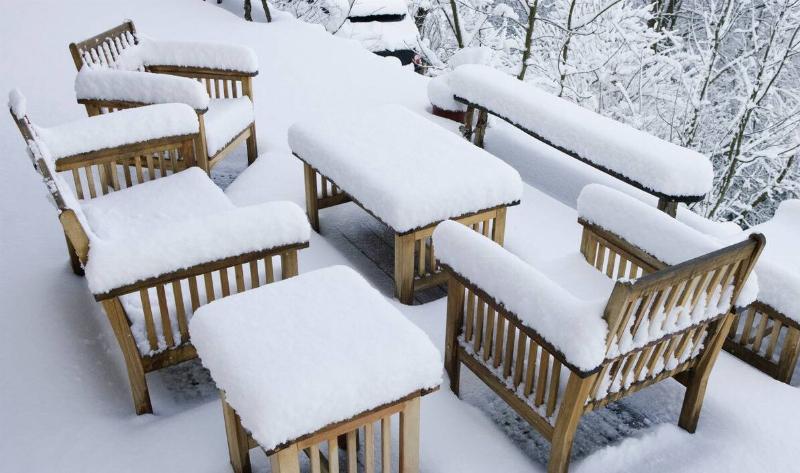 Wooden patio furniture covered in snow.