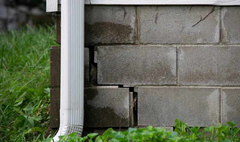 A home's brick foundation with cracks in the mortar.