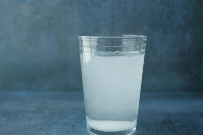 dirty glass of water against black background .