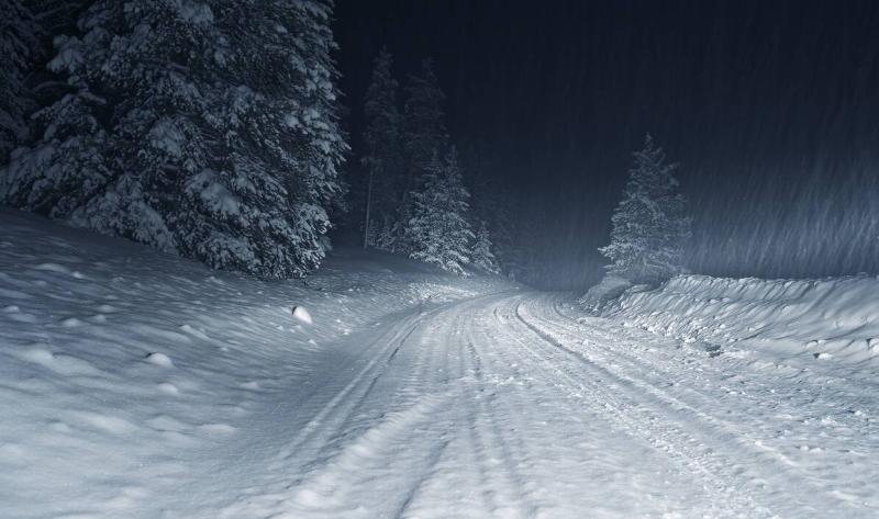 A snow-covered road at night.
