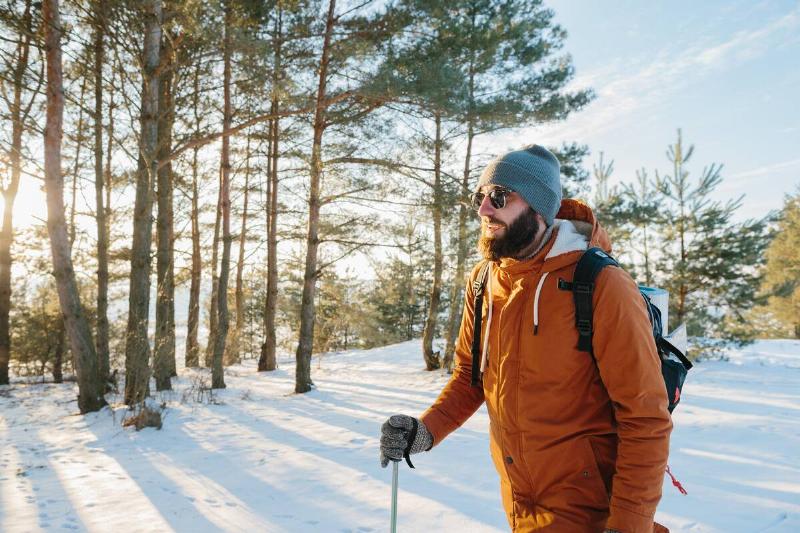 Winter landscape, a man with a backpack and warm winter clothes in the forest, traveling in the mountains.