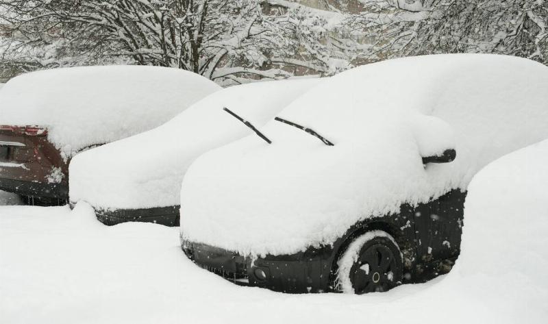 Cars in a parking lot piled high with snow.