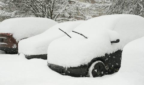 Cars in a parking lot piled high with snow.
