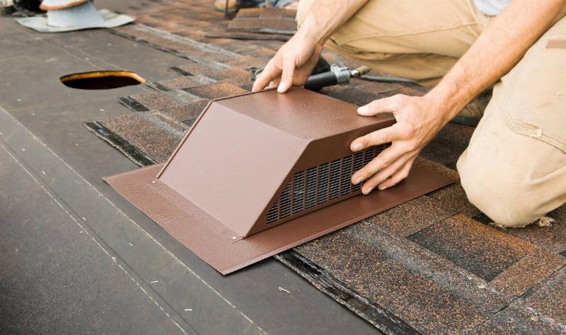 A repairman handling a furnace exhaust vent.