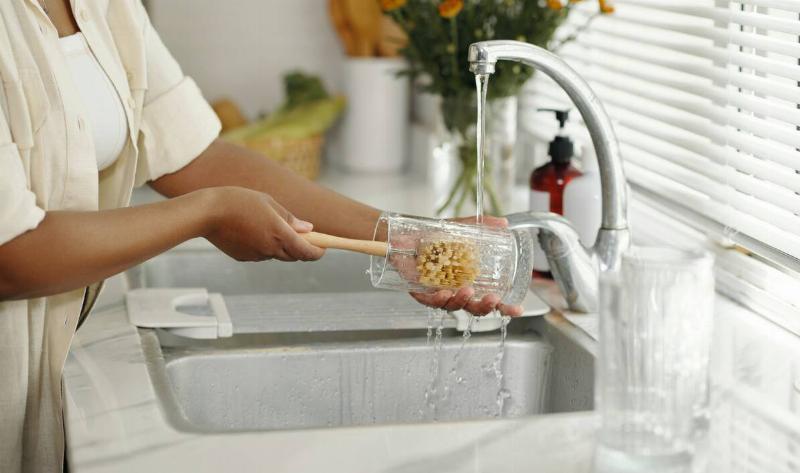 A woman using a brush to clean out a vase.