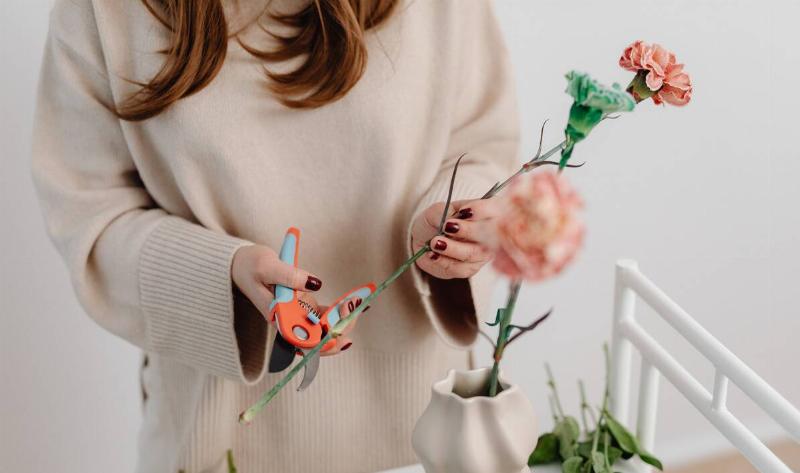 A woman trimming the end of a cut flower.