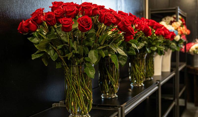 A row of large rose bouquets in vases.