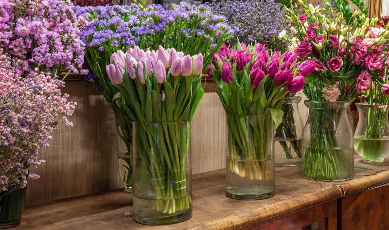 Rows of different bouquets of flowers in vases.