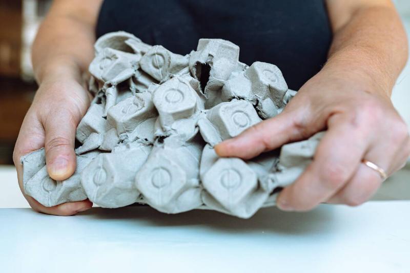 woman's hands press an egg carton out of paper for further recycling  into paper. Waste separation at home, zero waste, save space