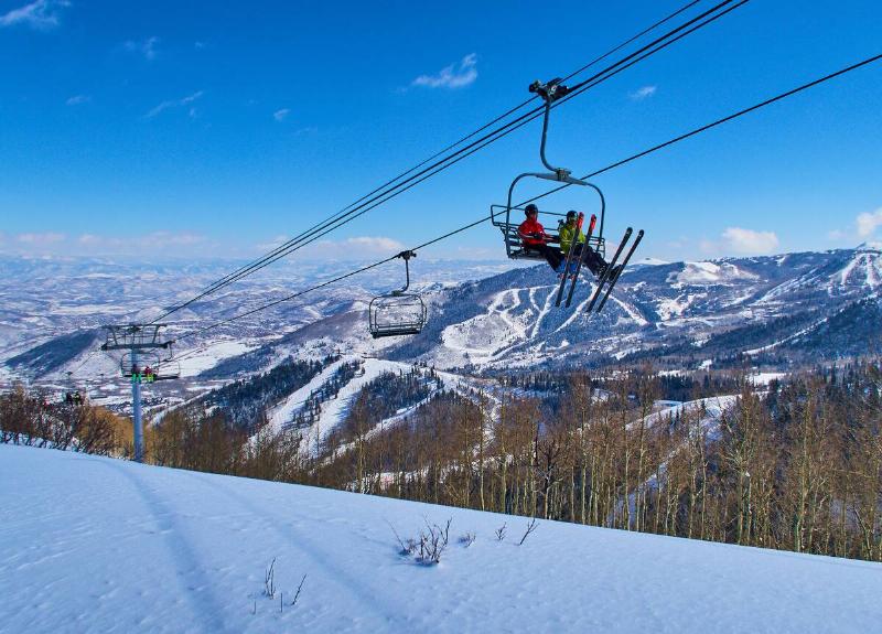 Skiers are sitting in a chair lift with panoramic view of the Wasatch Range in the Rocky Mountains on March 02, 2015 in Park City, Utah, United States.