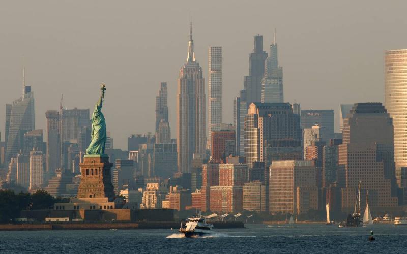 The sun sets on the Statue of Liberty and the Empire State Building in New York City on July 28, 2025, as seen from Bayonne, New Jersey.