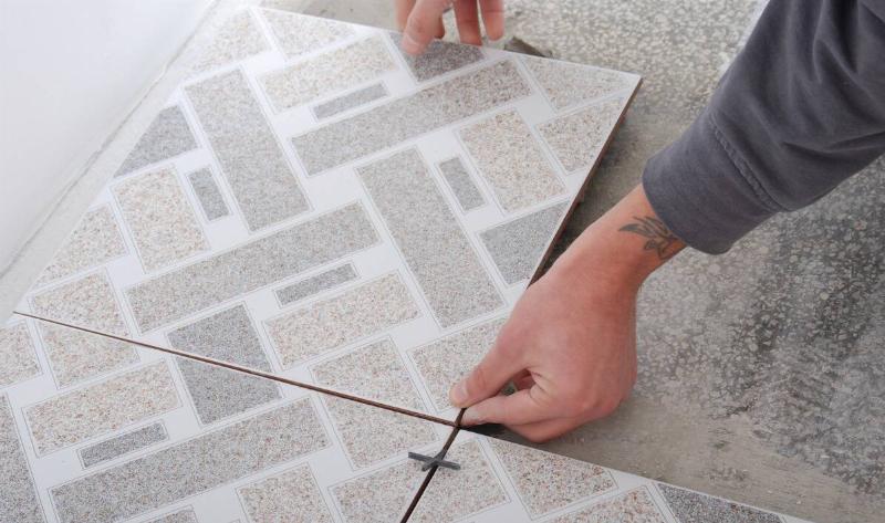 A person laying a flooring tile down.
