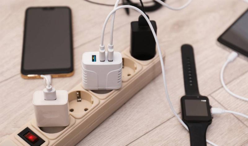 A few devices plugged into chargers which are plugged into a power strip.