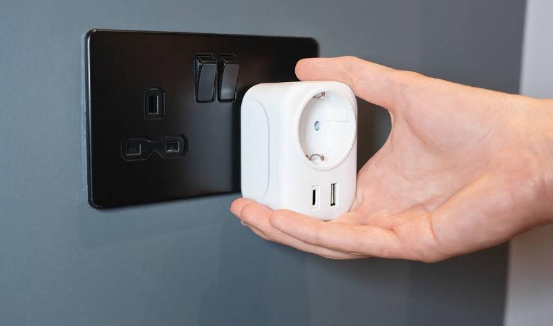 A person plugging an adapter into a wall socket.