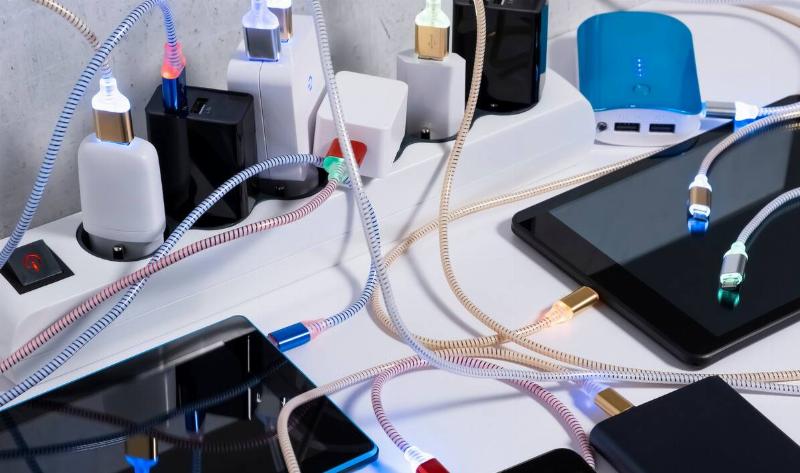 A power strip filled with plugged in cables that are charging many devices.