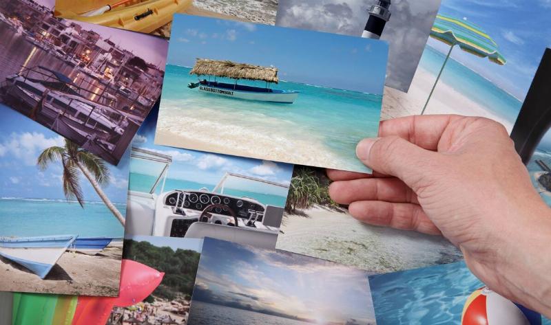 A person holding a photo stop a table covered with other photos.