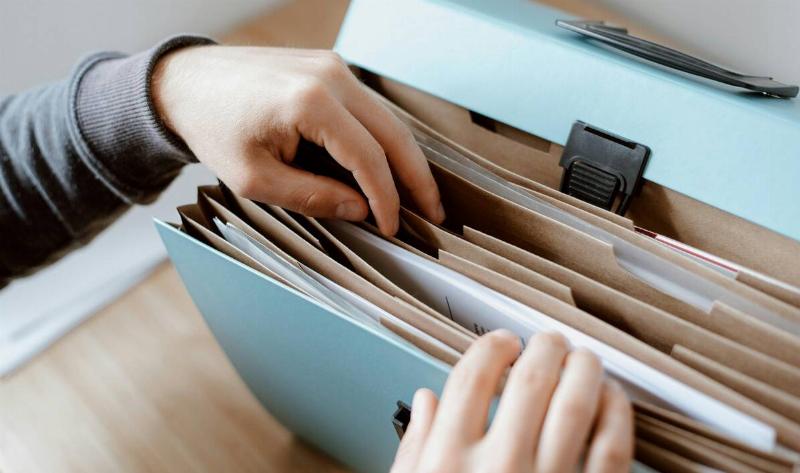 A person looking through a file folder of papers.
