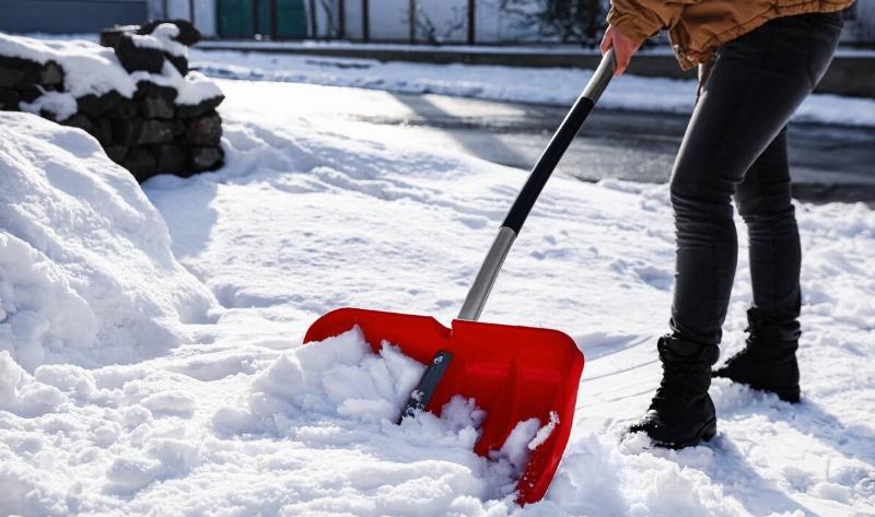 A person shoveling snow with a red shovel