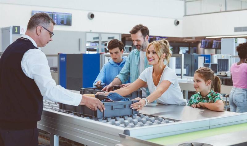 A family hanging their bins of items to TSA security to check.