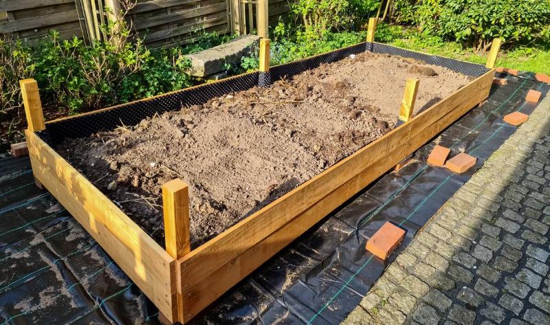 A half-built raised garden bed with dirt in it.