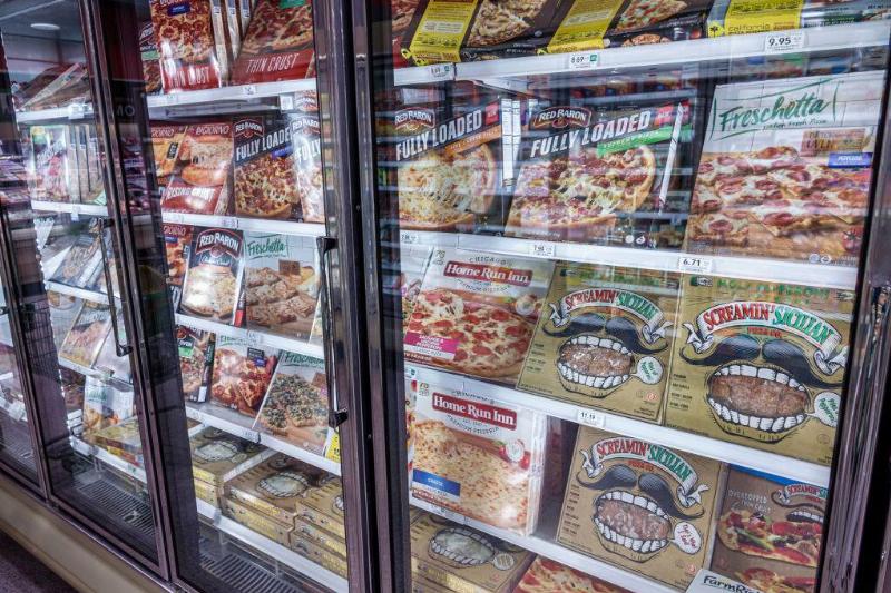 Rows of frozen pizza in a grocery store freezer