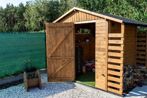 A wooden garden shed standing on a concrete foundation in a garden.