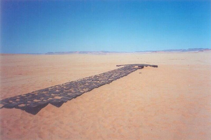 The eight bells with a large arrow mark a system of markings made from a large number of petrol drums, which were used to guide British aircraft as they landed in the Great Sand Sea during World War II.