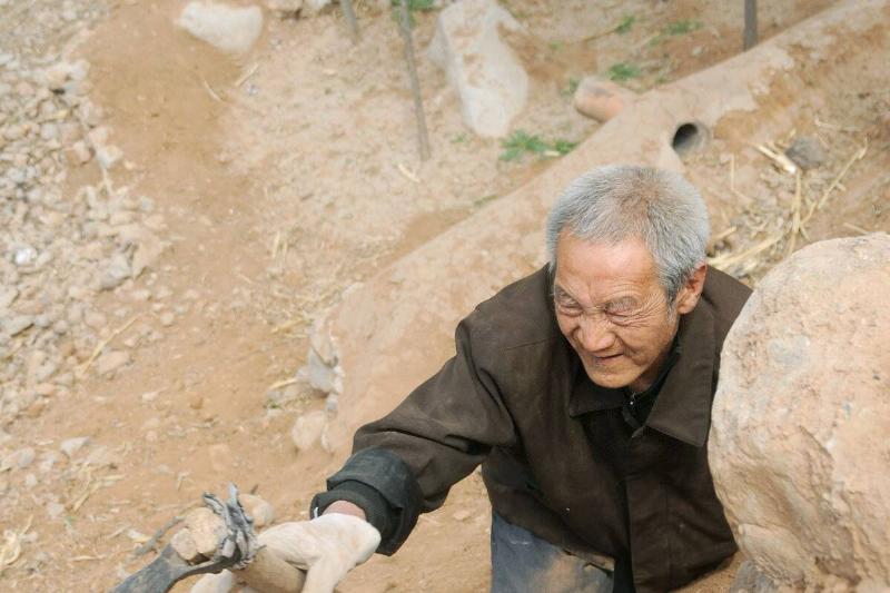 Ma Sanxiao using a hoe to climb up a hill in a village of Jingxing County in north China's Hebei Province.