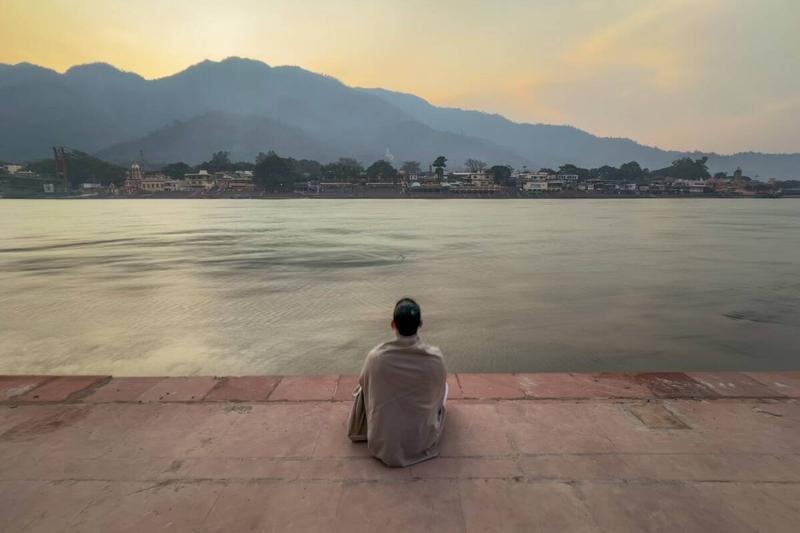 A woman sitting at the river Ganges in Rishikesh, Uttarakhand, India.
