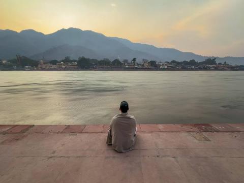 A woman sitting at the river Ganges in Rishikesh, Uttarakhand, India.