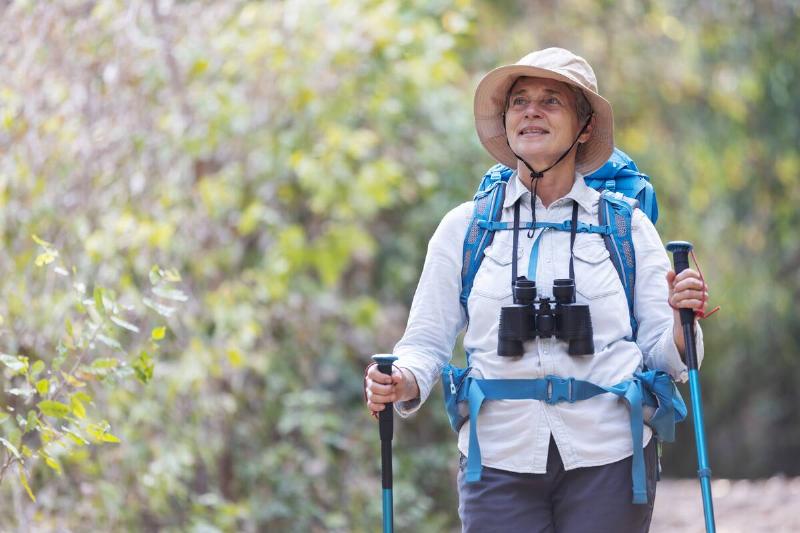 A senior woman walking with walking sticks. 
