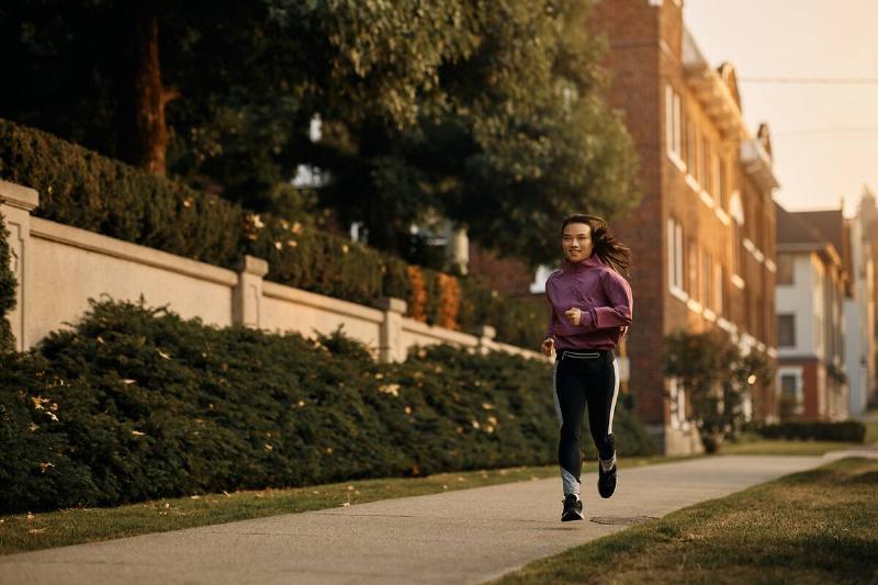 Young Asian female athlete jogging on city street.
