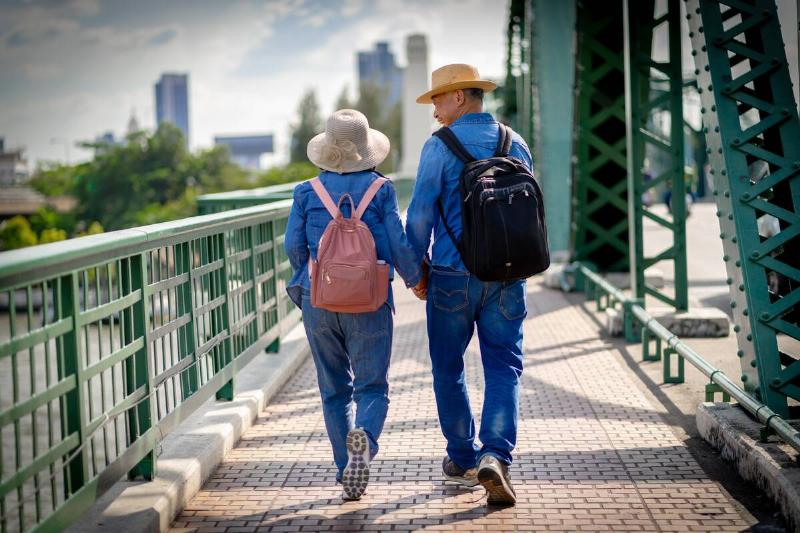 Asian retired couple happily walking across a bridge. 