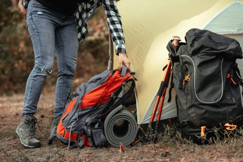 A person setting a packed backpack down near a tent. 