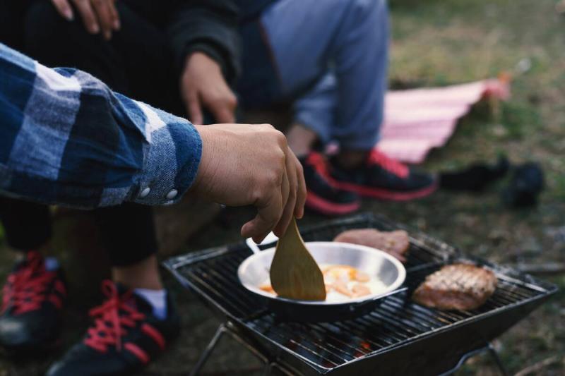 People cooking over campfire. 