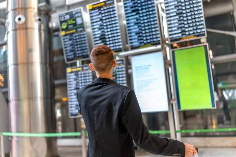 A man looking at a timetable display in an airport. 