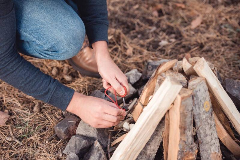 A man kindling bonfire in a forest.