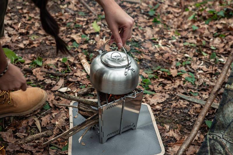 A metal kettle placed on a portable bushcraft stove.